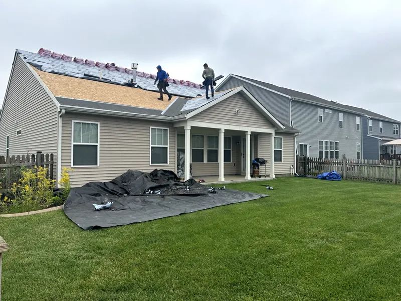 Roofing crew working with tarps protecting the lawn and landscaping below