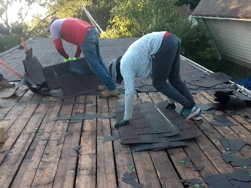 Crew tearing old shingles off a roof down to bare decking