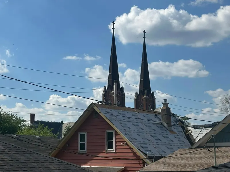 Roof underlayment installed on an older home with historic church steeples in the background